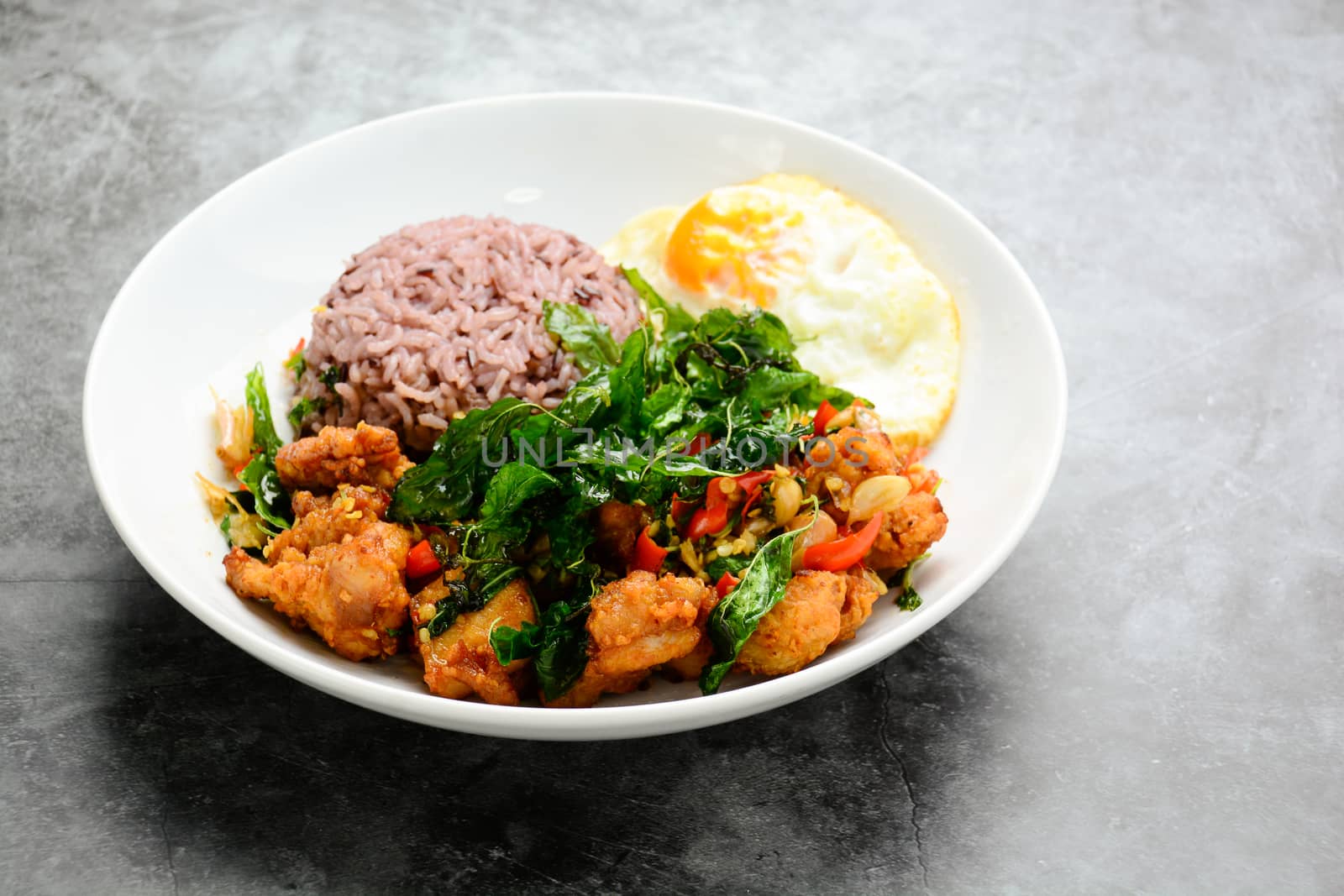 Crispy chicken cooked with green basil, served with steamed rice and fried egg, hot and spicy dish with basil leaves.
