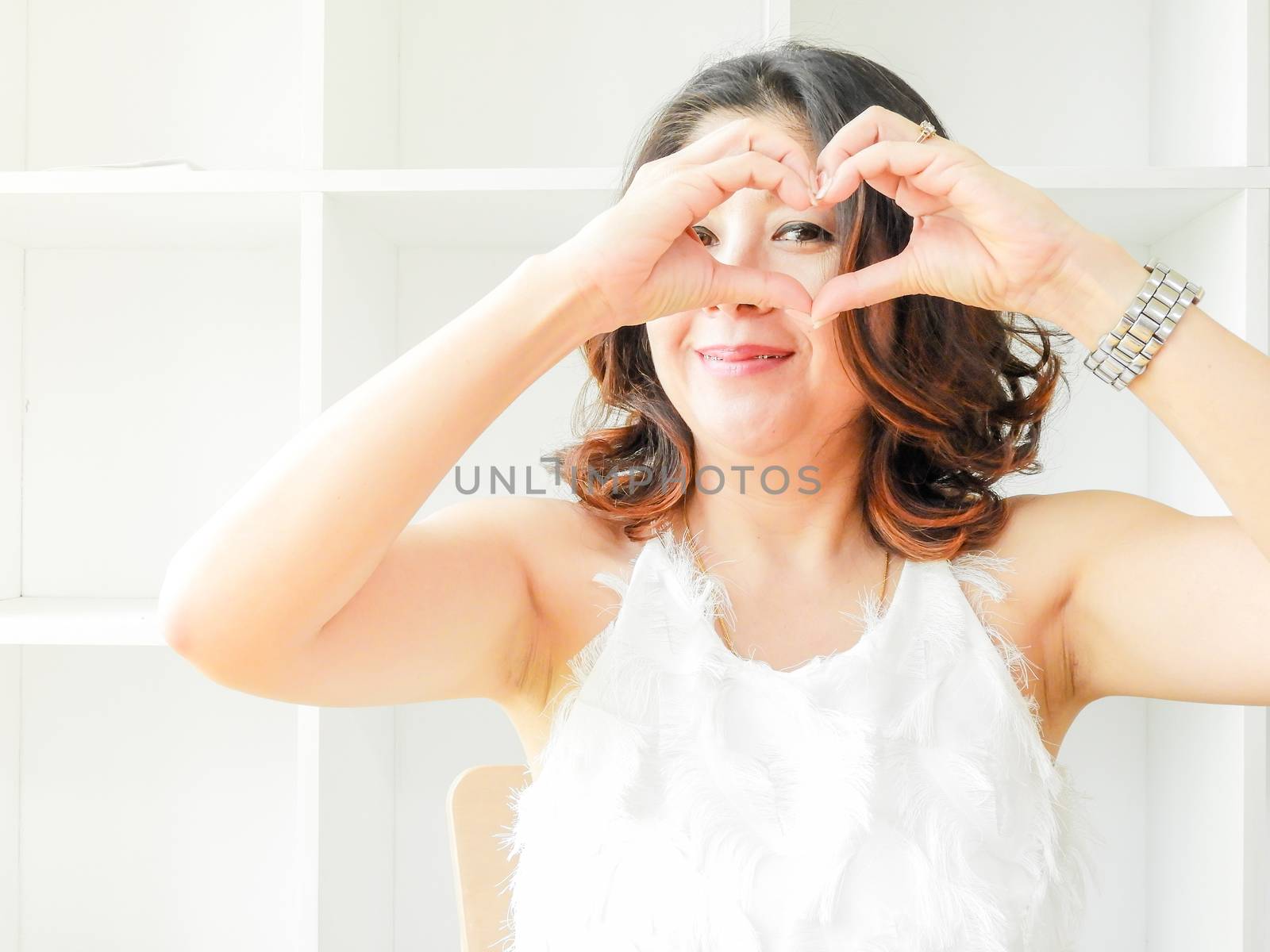 Pretty woman with smiley happy face making heart shape by her ha by yuiyuize