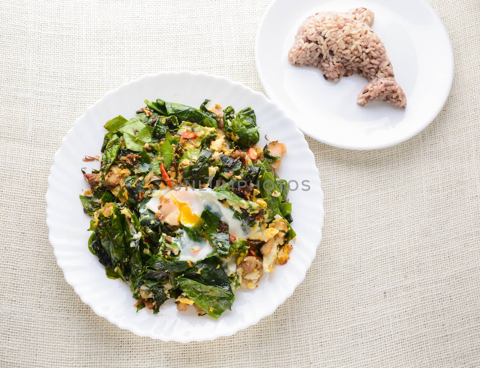 A white plate of delicious Stir-Fried Baegu Leaves or Melinjo with Eggs, served with steamed rice.