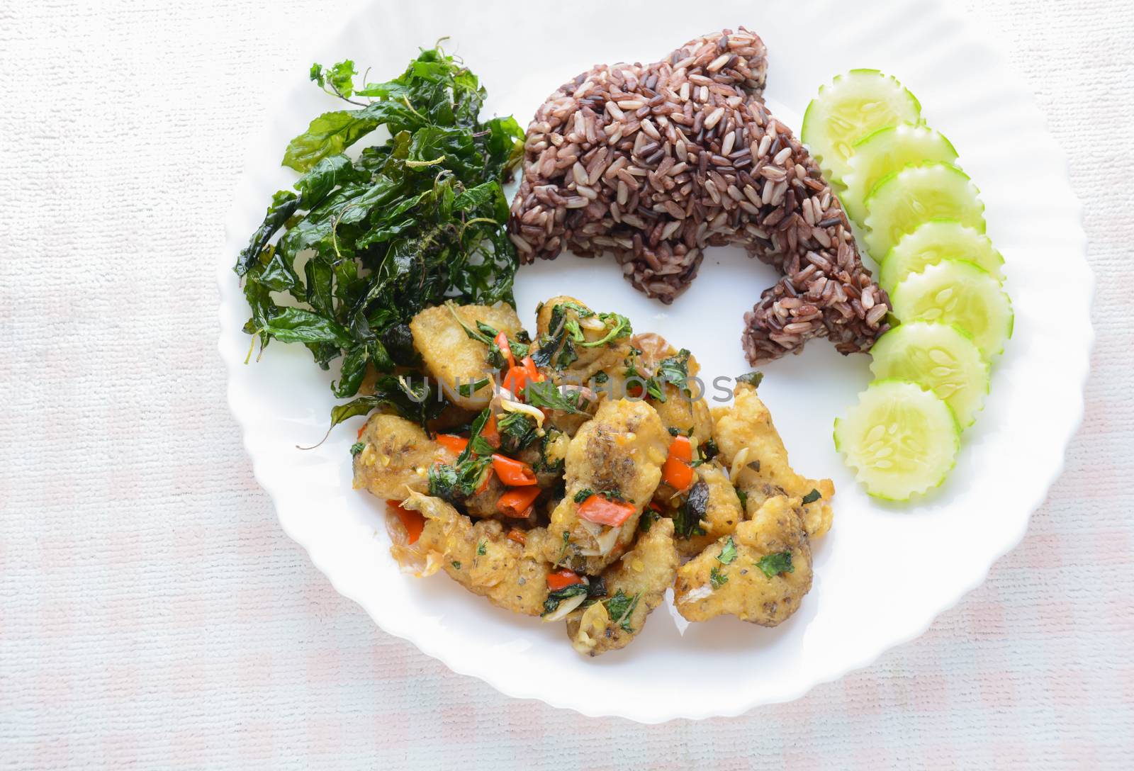 Stir fried fish with chili and basil, served with steamed rice and cucumber, hot and spicy dish.