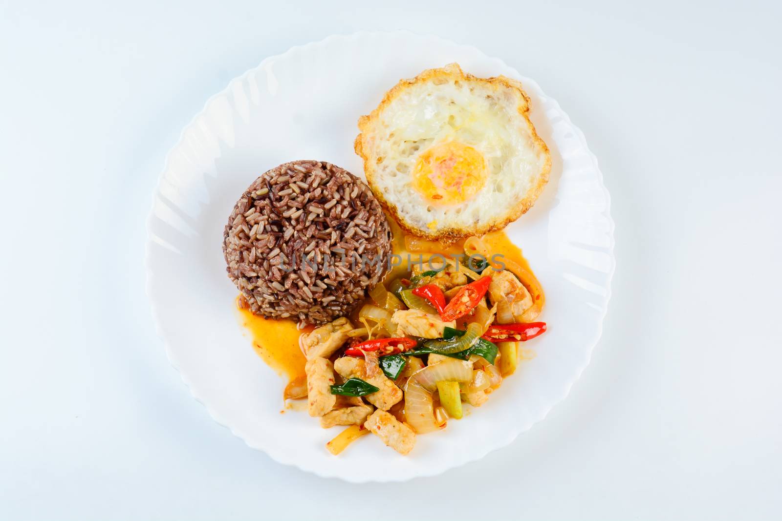 Stir fry chicken sweet onion and peppers, served with brown rice and fried egg on white plate
