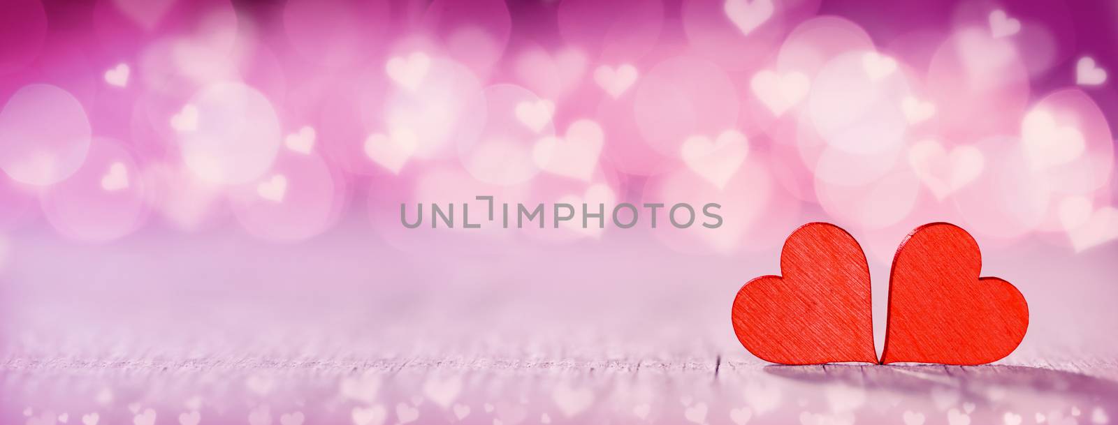 Two wooden hearts on pink glowing bokeh hearts background for Valentines day