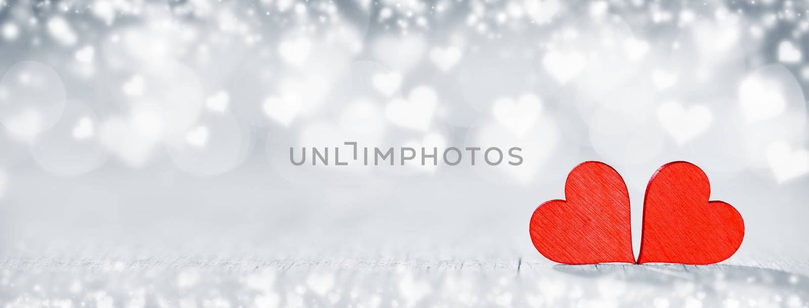 Two wooden hearts on silver glowing bokeh hearts background for Valentines day