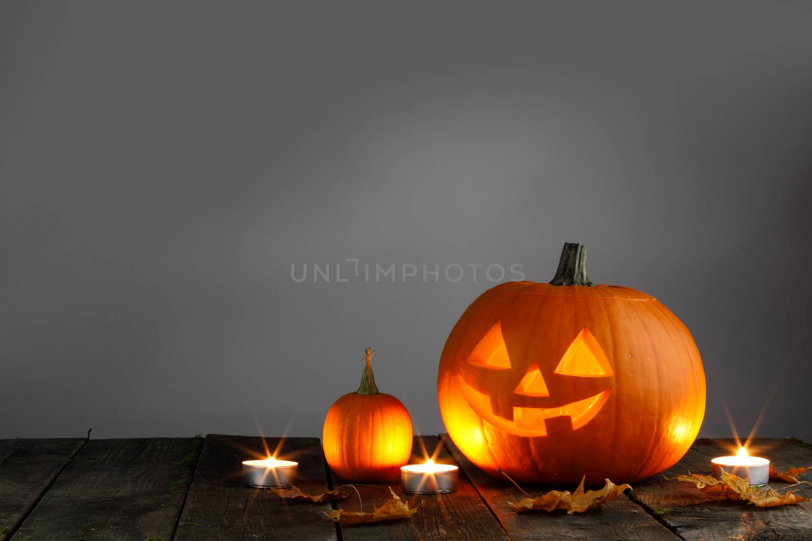 Halloween pumpkin head jack o lantern and candles on wooden background