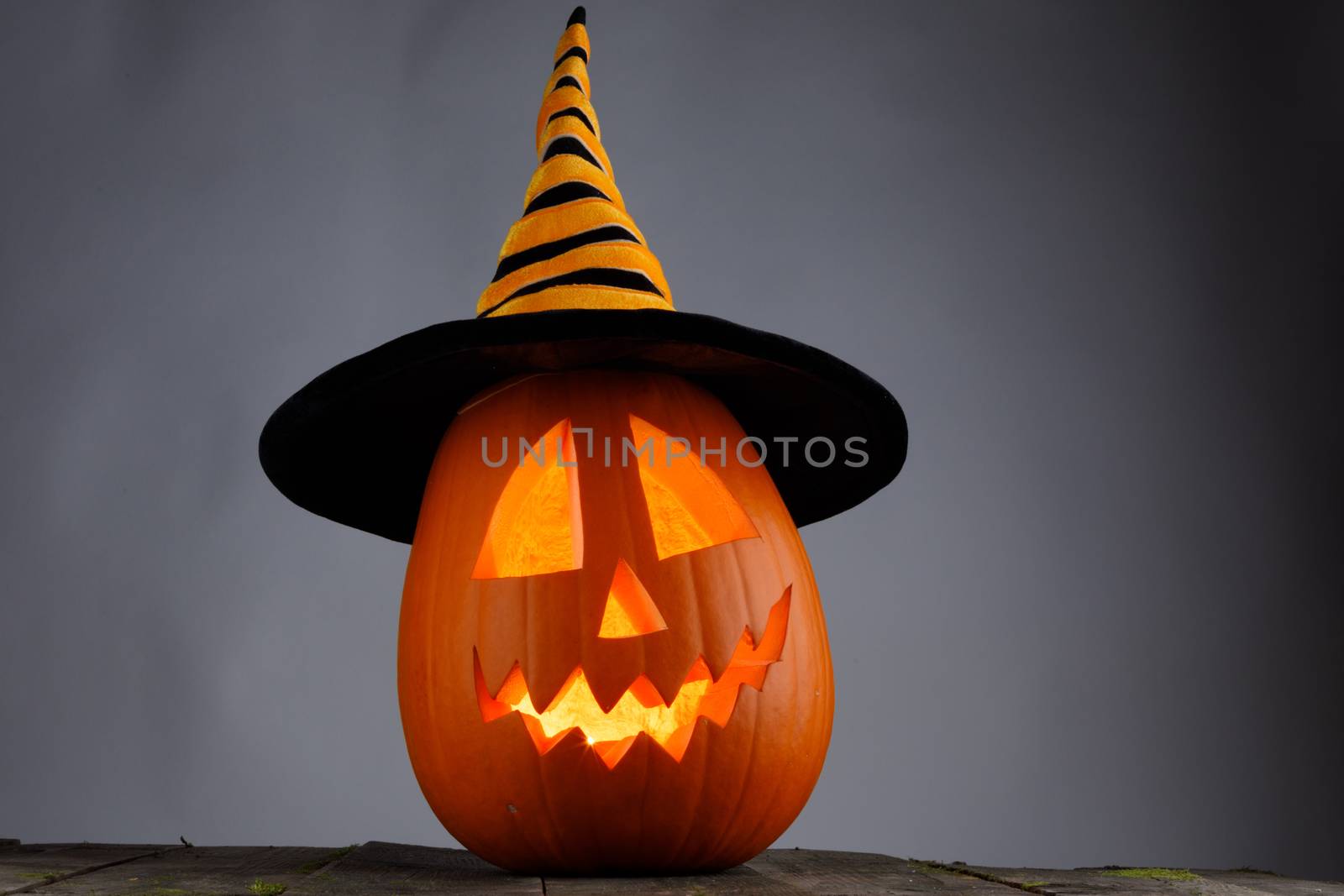 Jack O Lantern Halloween pumpkin with witches hat on wooden background