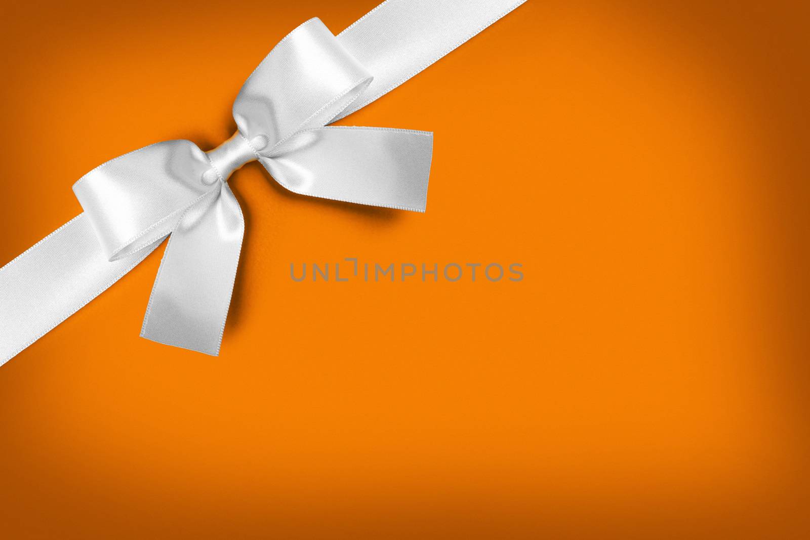 White gift bow on orange background with copy space