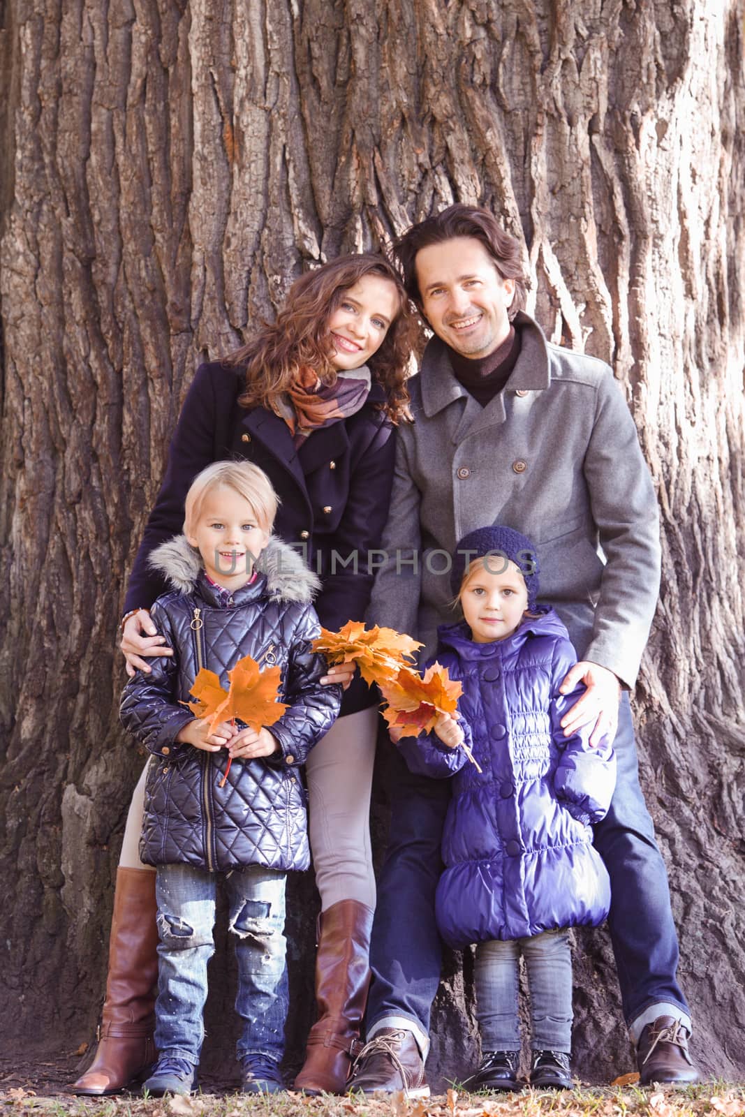 Happy smiling family of parents and children in autumn park