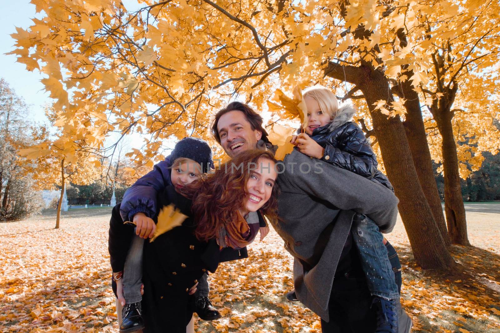 Happy smiling family of parents and children having fun hugging in autumn park