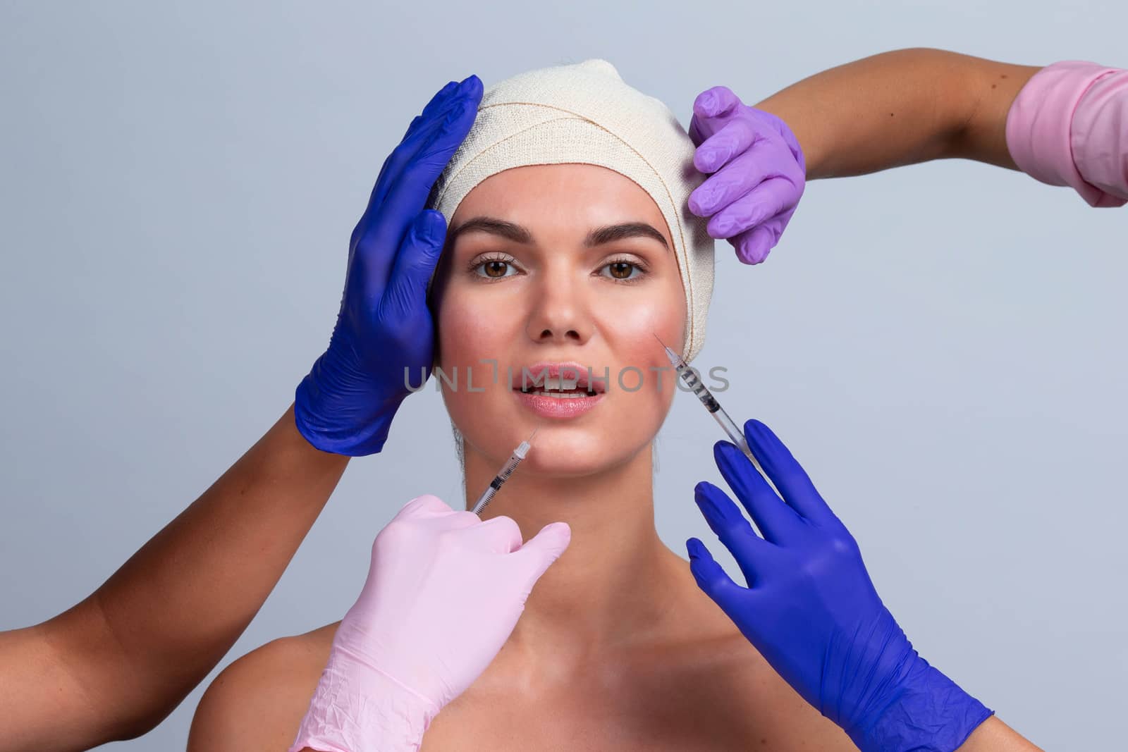 Attractive young woman gets cosmetic injection. Doctors hands making an injection in face. Beauty Treatment.