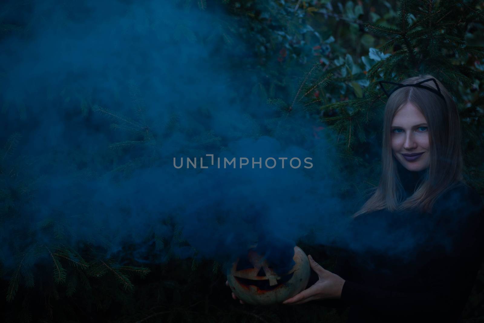 Woman with pumpkin in smoke dark halloween background with copy space for text