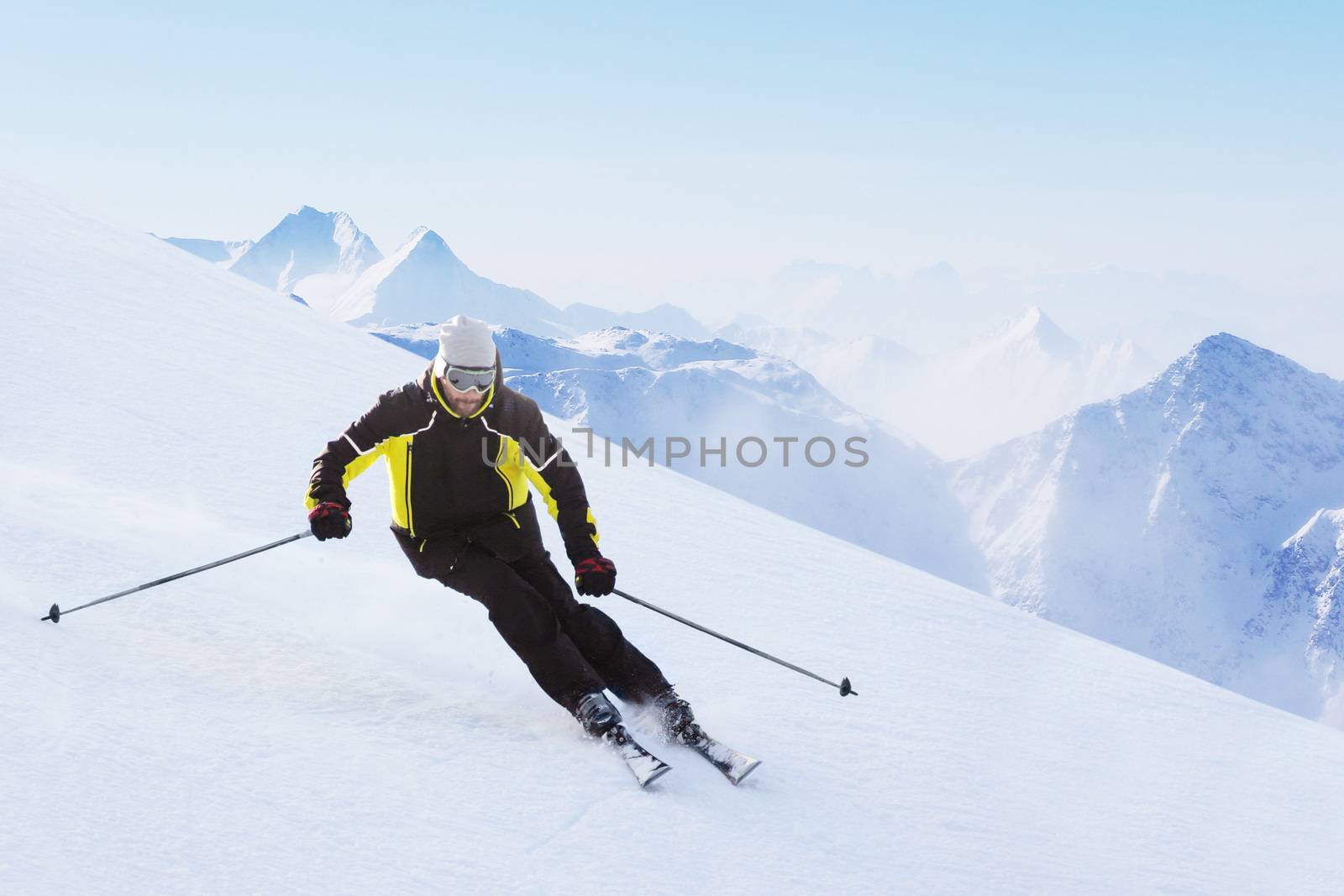 Alpine skier on piste running downhill in beautiful Alpine landscape. Blue sky on background. Free copy space for text