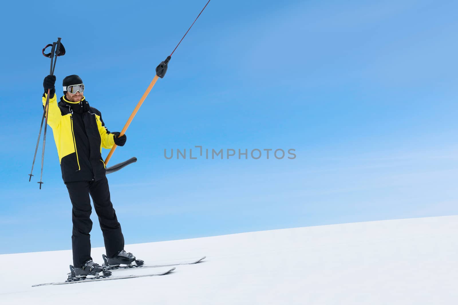 Happy skier using T-bar ski drag lift by destillat