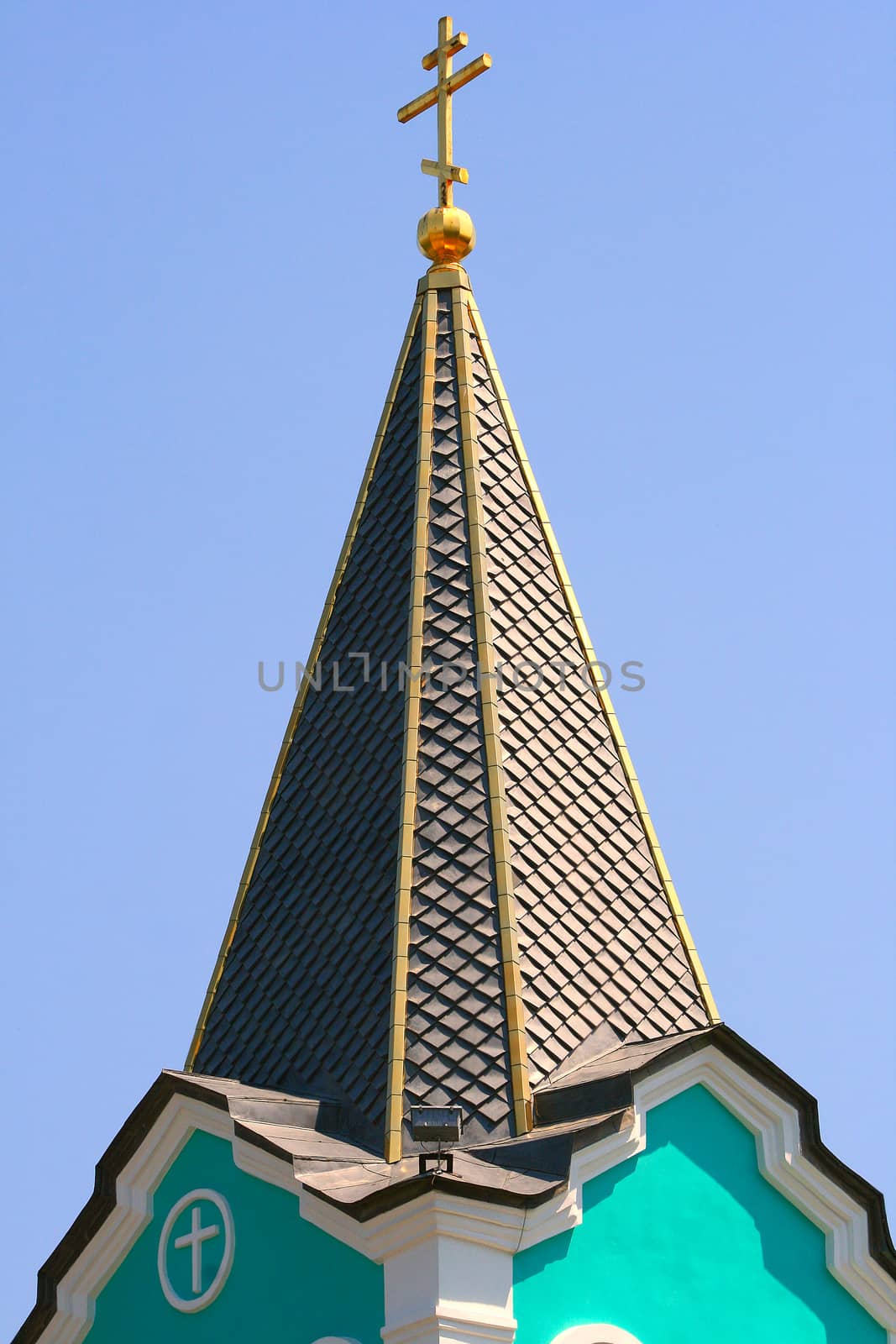 Close-up of the bell tower with a cross against the sky.