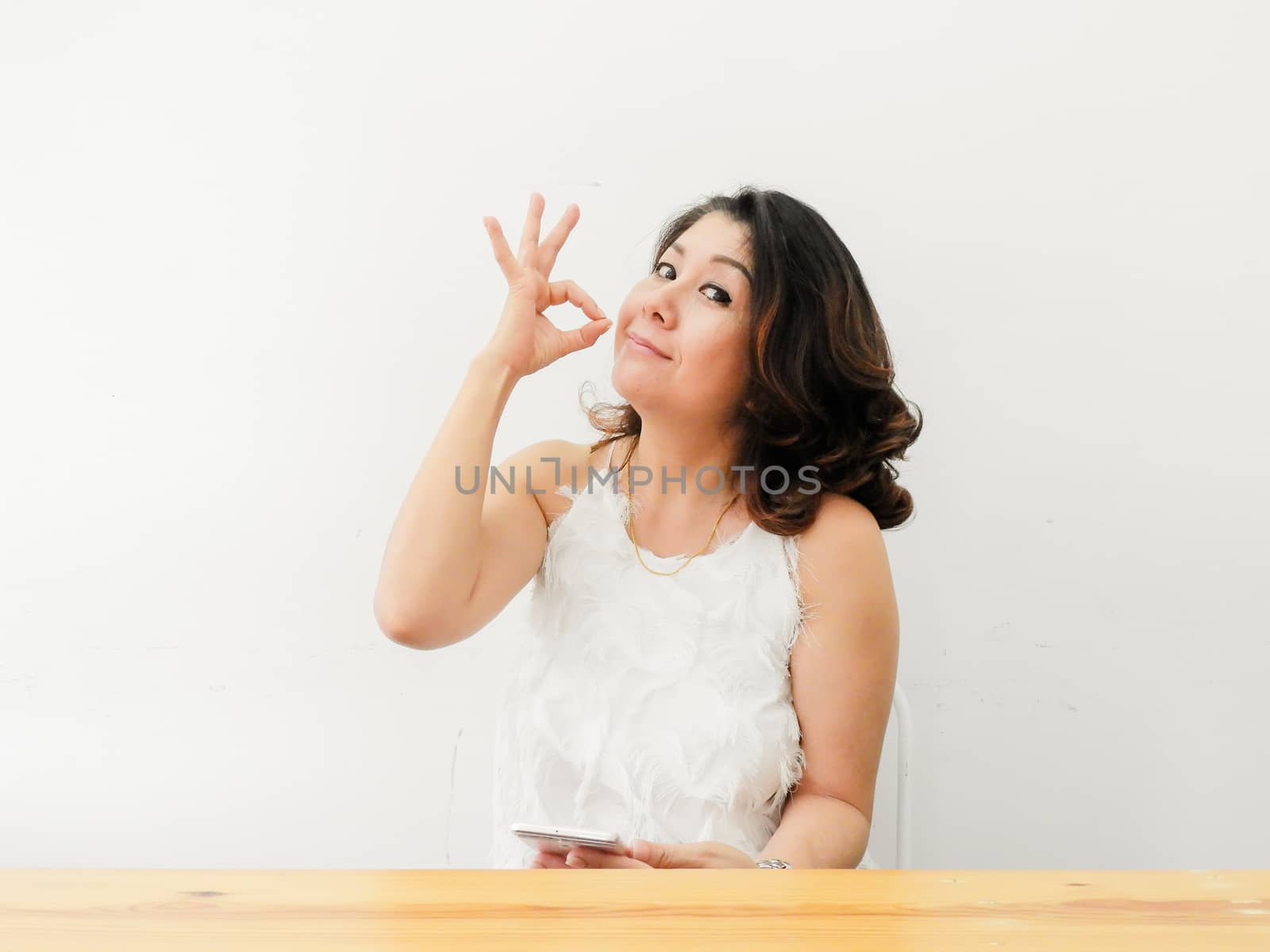 Beautiful woman showing OK hand sign smiling happy against white background.
