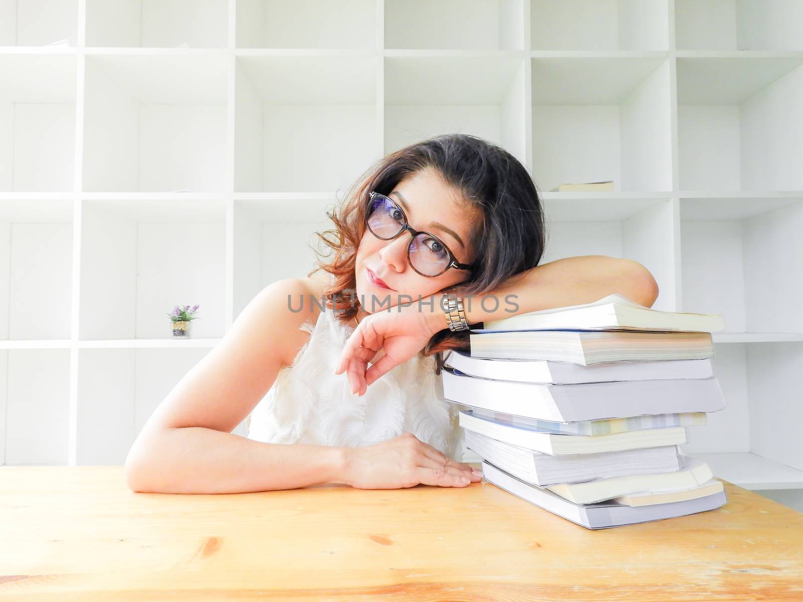 Beautiful women in glasses crushed on the table by a lot of book by yuiyuize