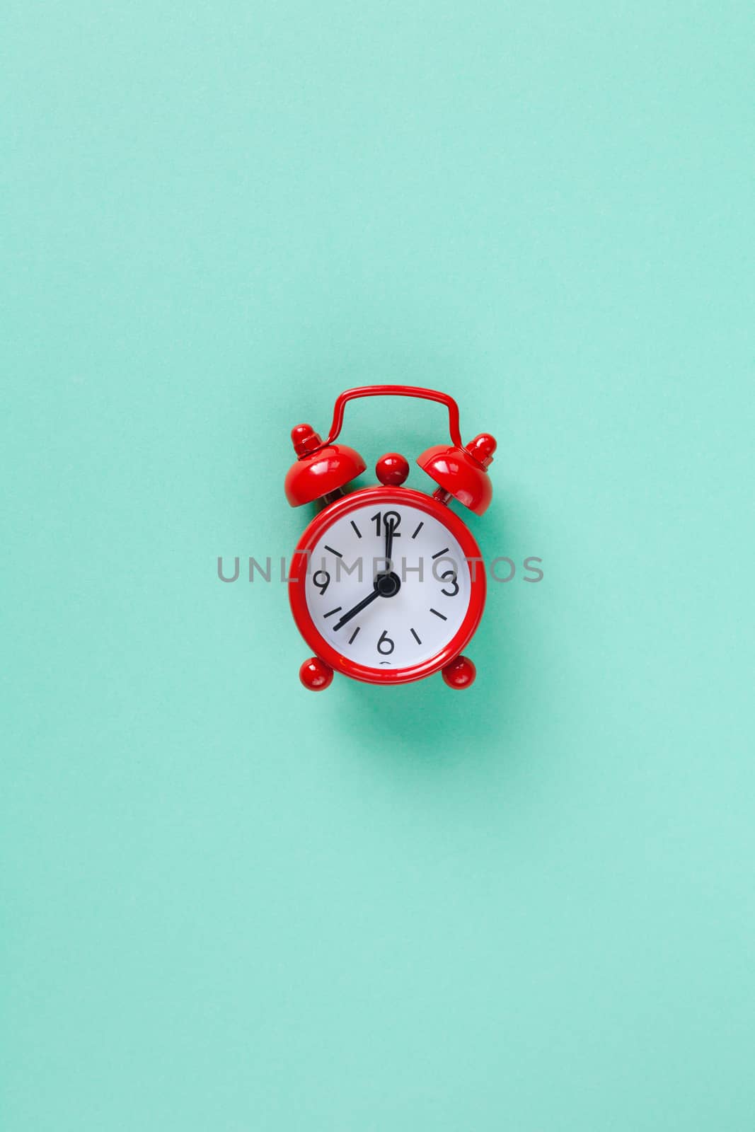 Red small alarm clock on pastel turquoise background with copy space, flat lay. Minimal style. Template for blog. Lifestyle. Time management concept, free time for important things. Vertical.