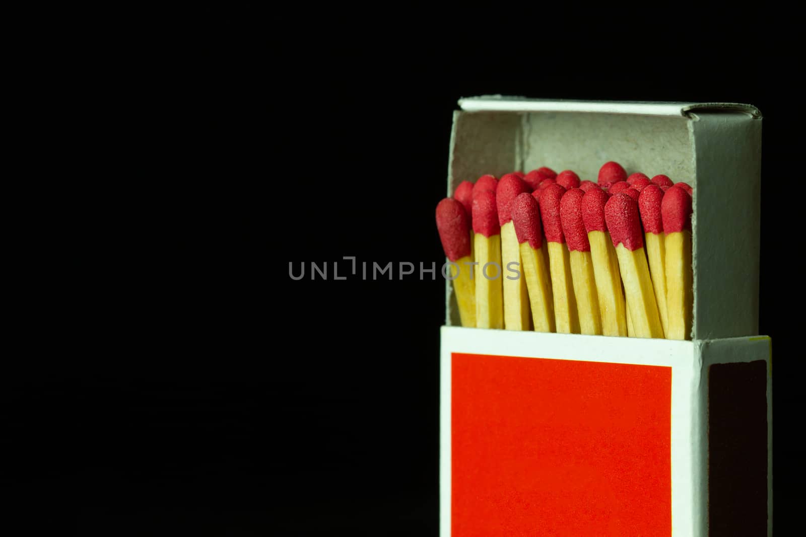Matches stick in red paper box on black background. Closeup and copy space.