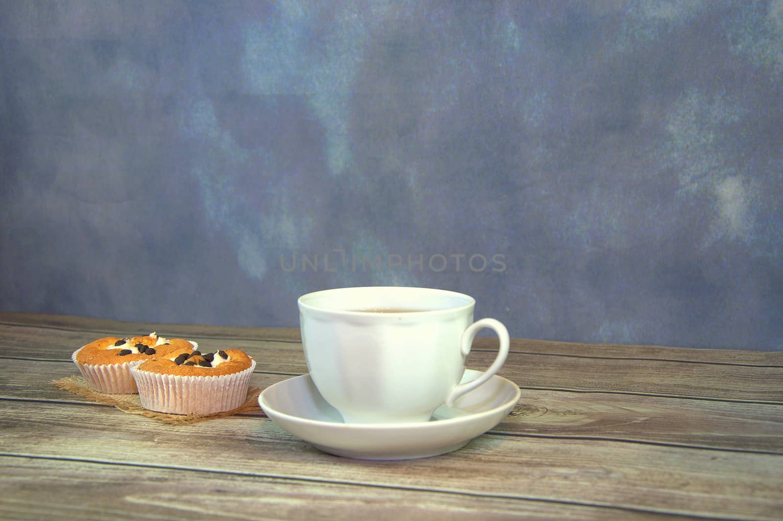 A cup of coffee and two cupcakes with chocolate on a textile napkin. Close-up.