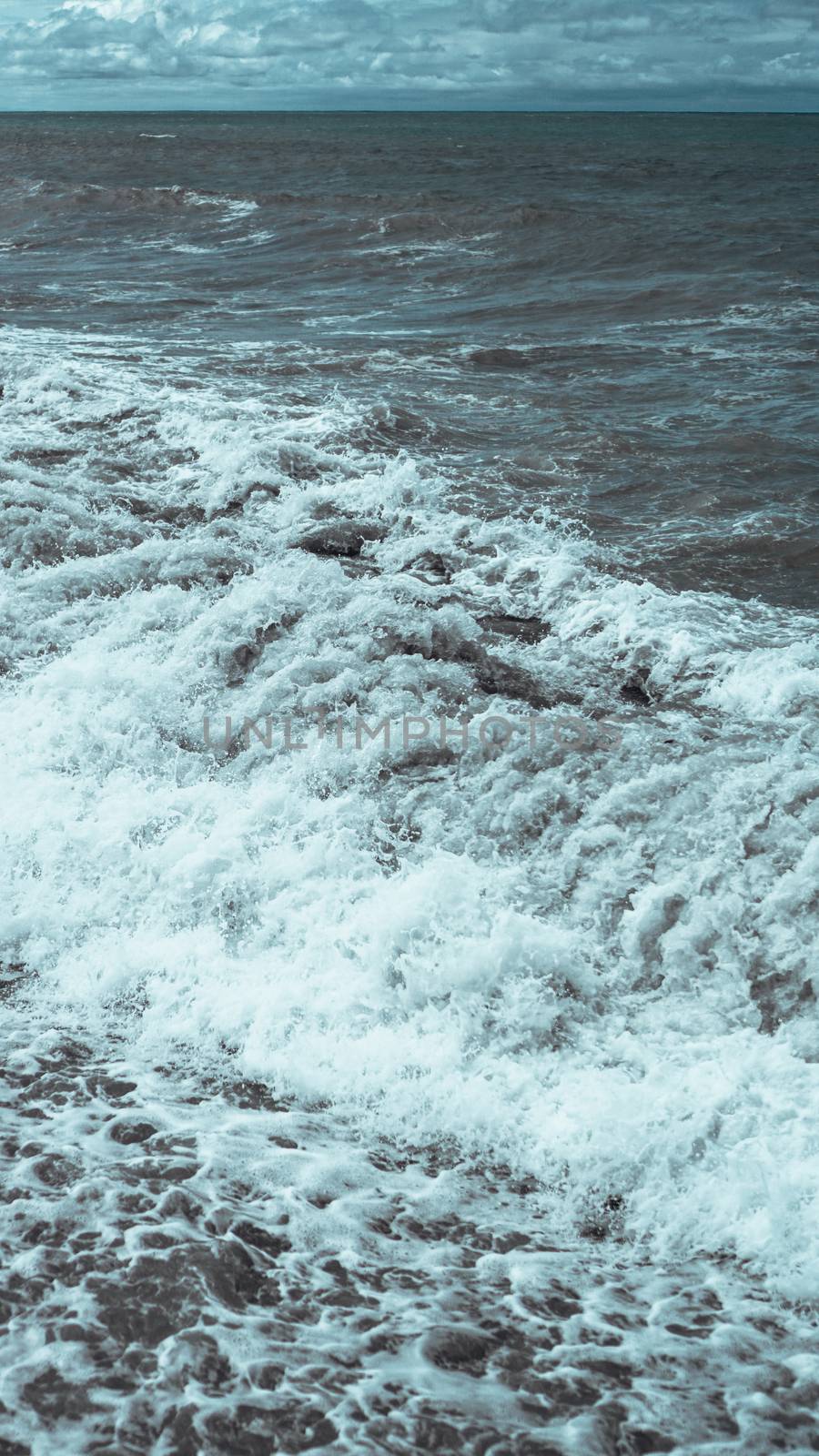 A breaking wave and stormy sea in a vertical panorama format.