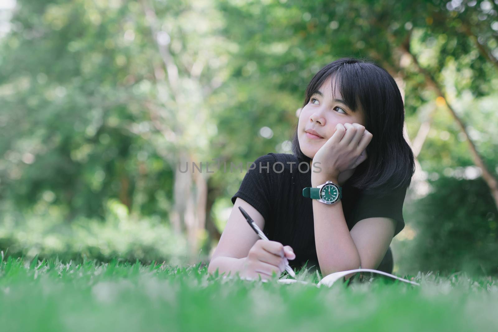 The girl is sitting in the lawn in the garden. by aekgasit