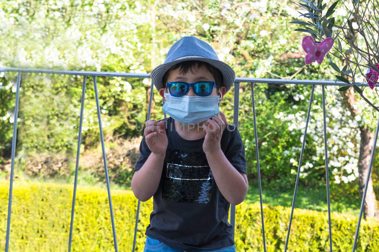 Little boy with a hat and sunglasses and respirator