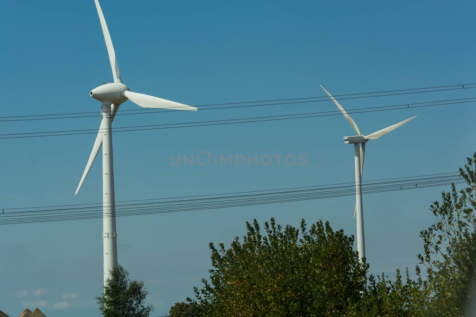 Windmill turbines with partially cloudy blue sky in the background. Wind turbines for renewable energies