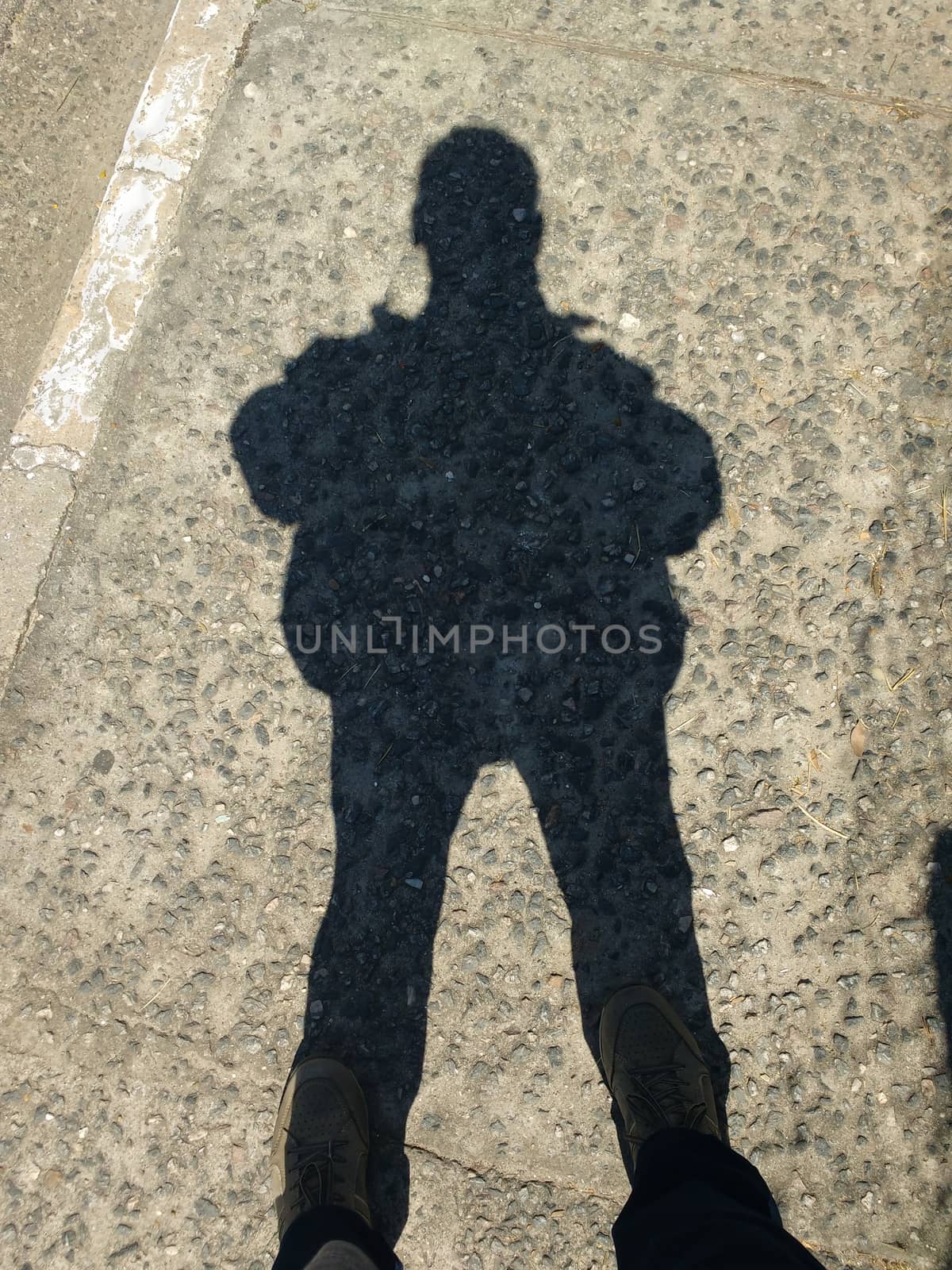 Shadow in silhouette of man standing in sunny day on rustic floor.