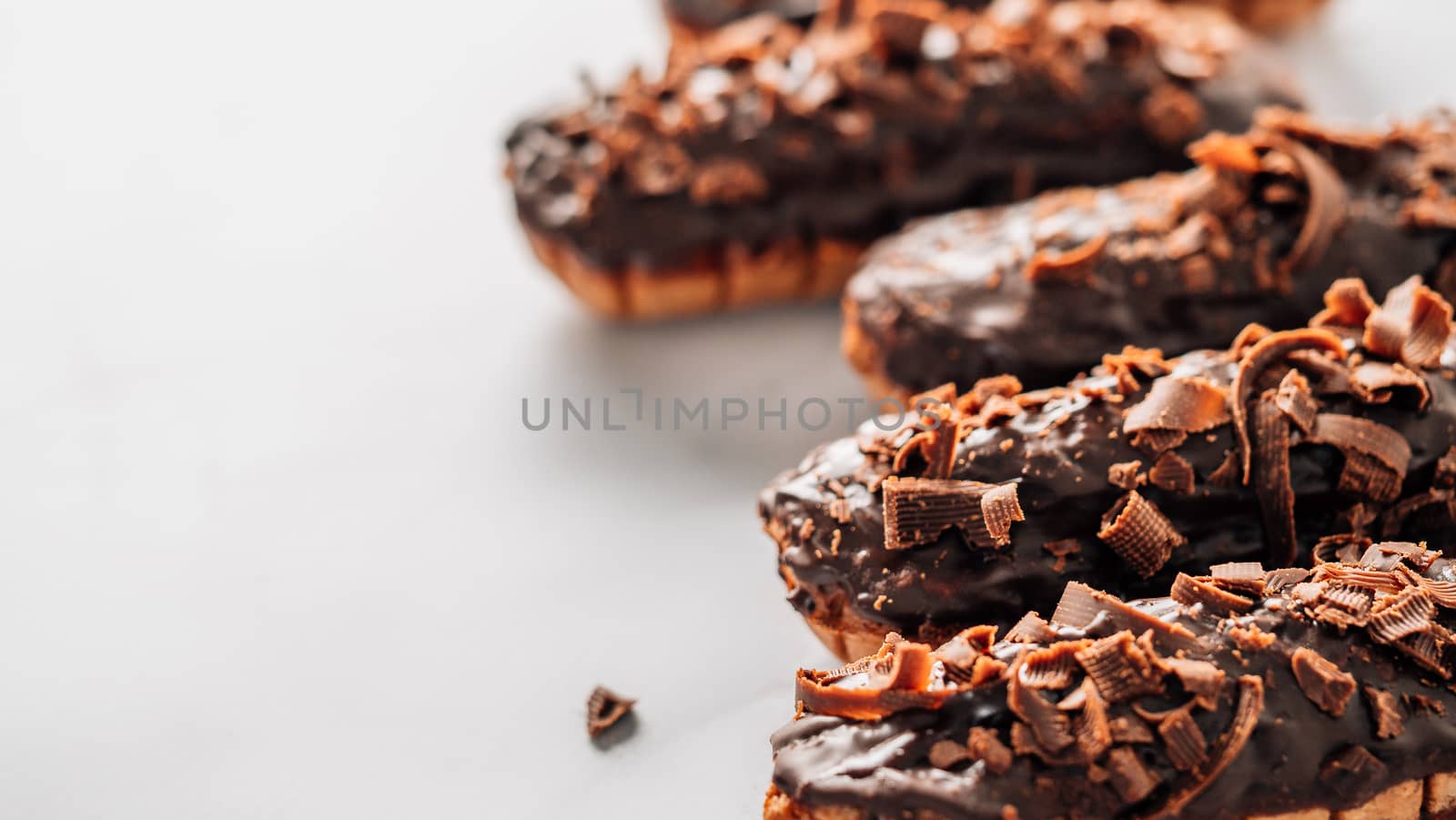 Set of homemade eclairs with chocolate on marble background. Close up view of delicious healthy profitroles with chocolate glaze. Copy space for text or design. Banner