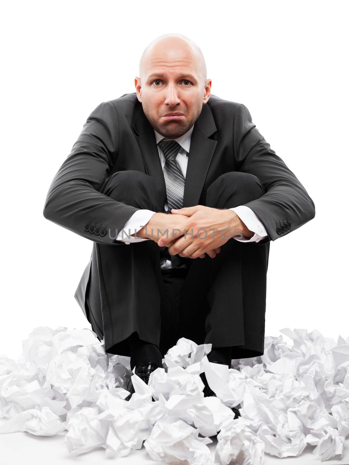 Businessman in depression sitting on crumpled torn paper document by ia_64