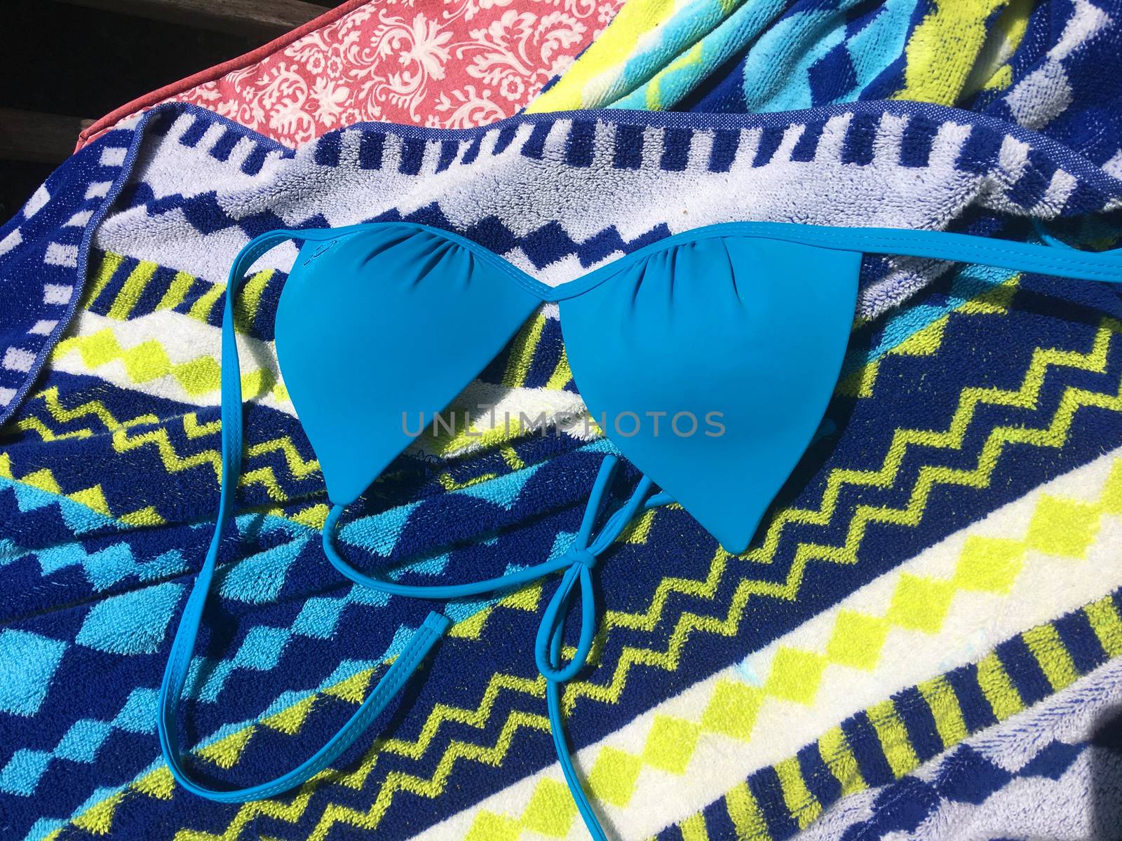 Swimsuit top on beach towel on vacation by illstudio