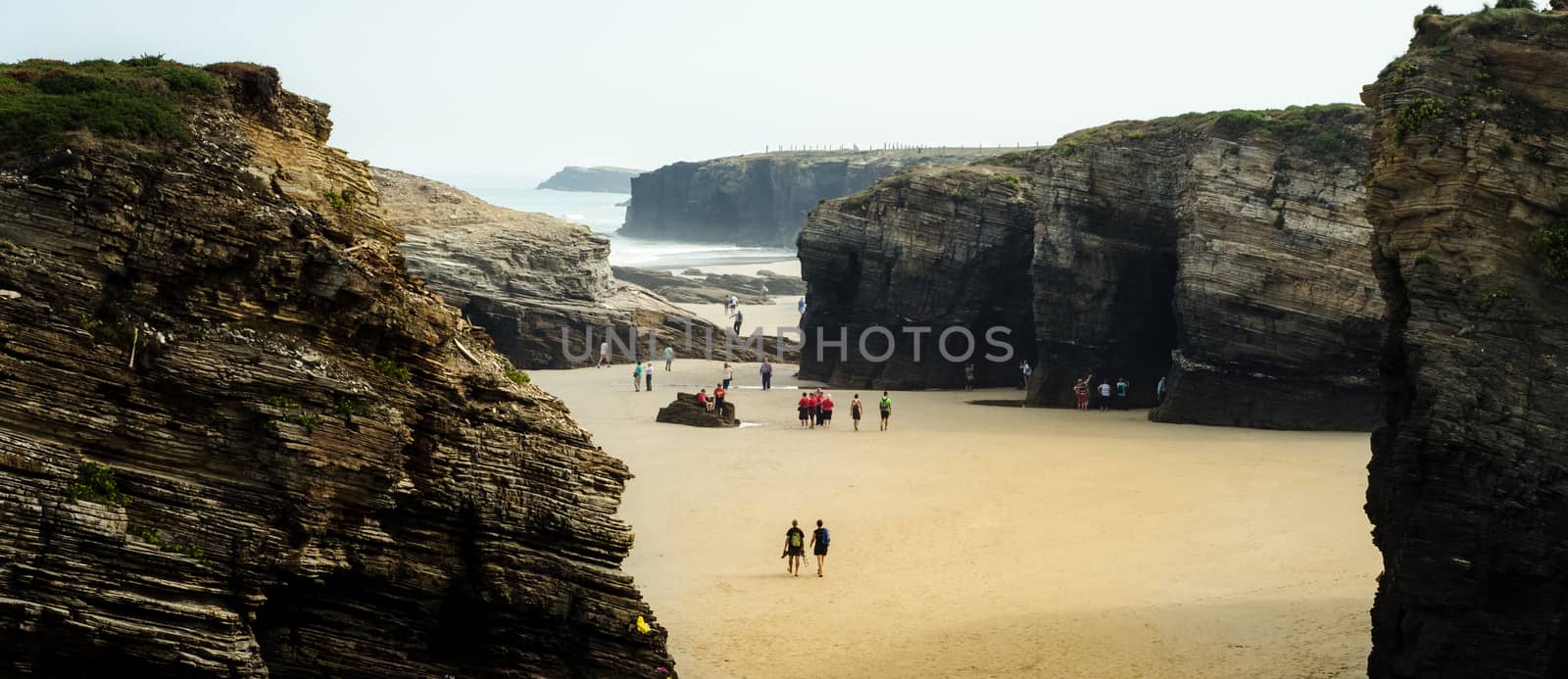 Cathedrals Beach's abrupt cliffs see people walking through them