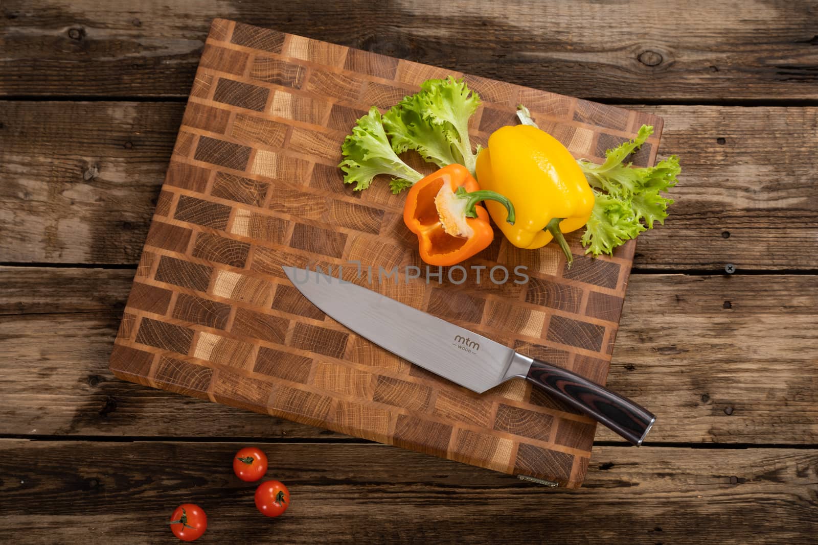 Red, ripe, bright tomatoes and peppers lie on a wooden cutting board near the kitchen knife. Cutting vegetables for cooking. Fresh, ripe, tasty, natural vegetable.