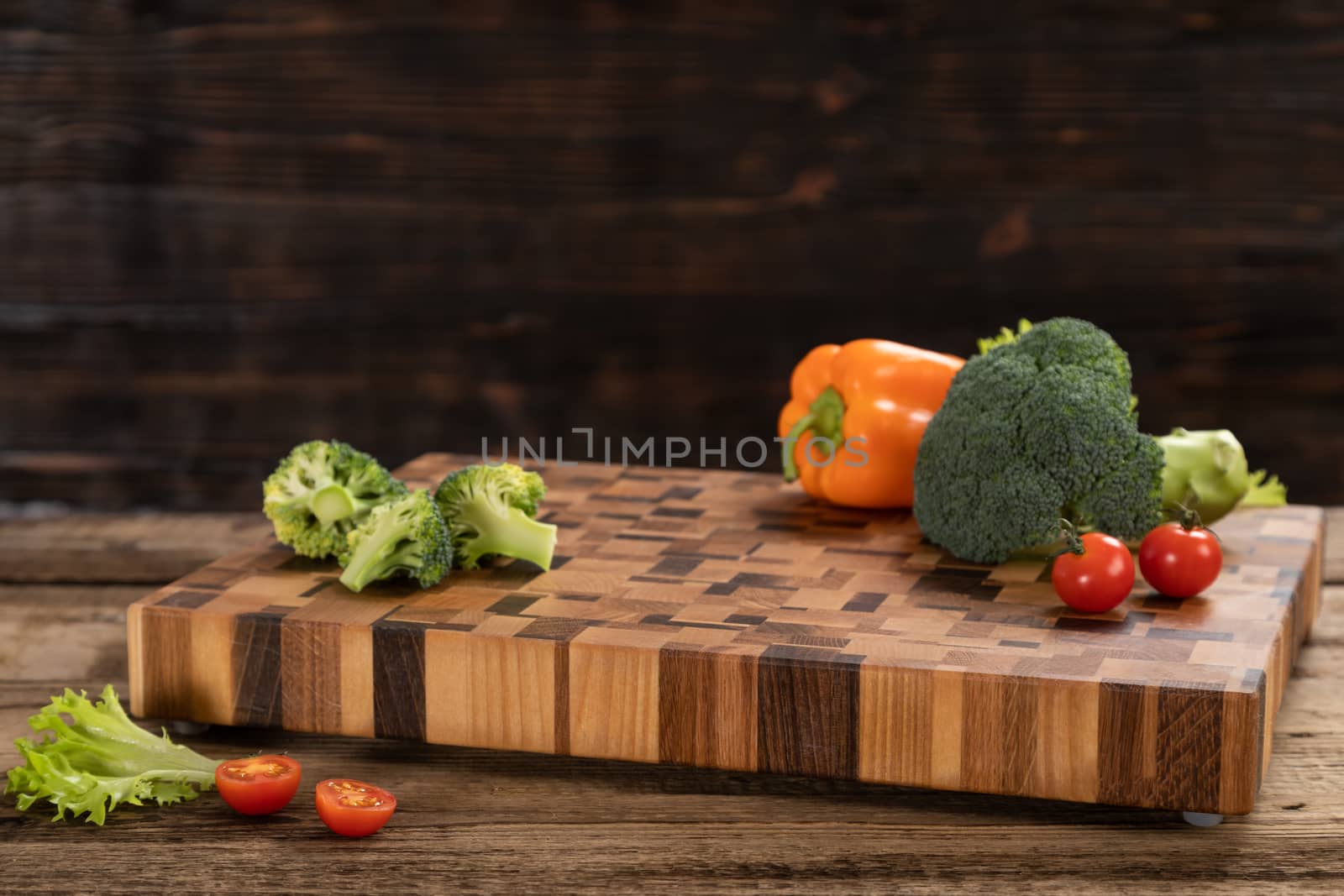 Bright ripe, broccoli, tomatoes and peppers lie on a wooden cutting board near the kitchen knife. Cutting vegetables for cooking. Fresh, ripe, tasty, natural vegetable.