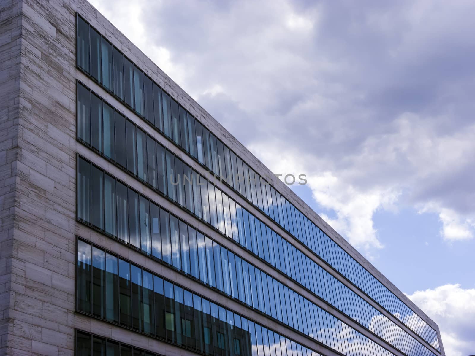 Cloudy sky reflected in the glass wall of a high building.