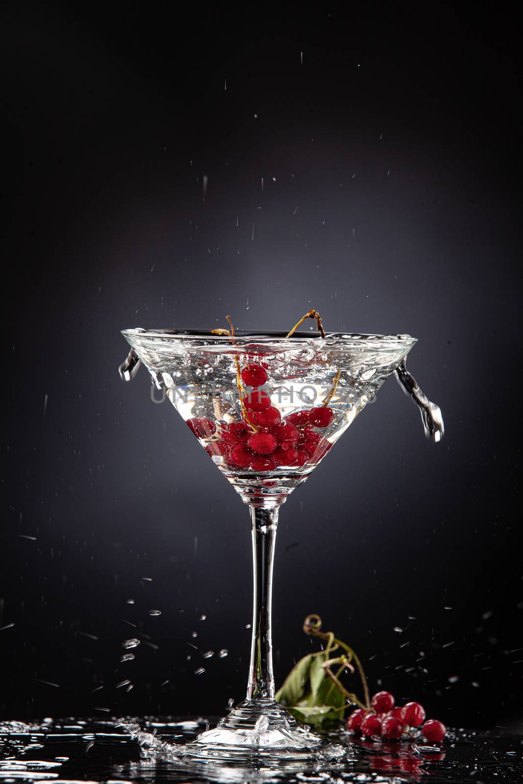 Bunch of red currant falling into the glass of water