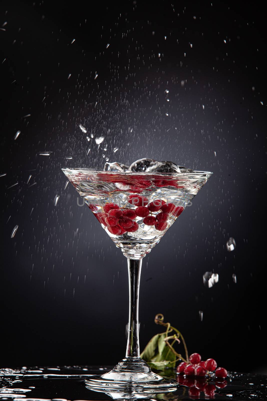 Bunch of red currant falling into the glass of water