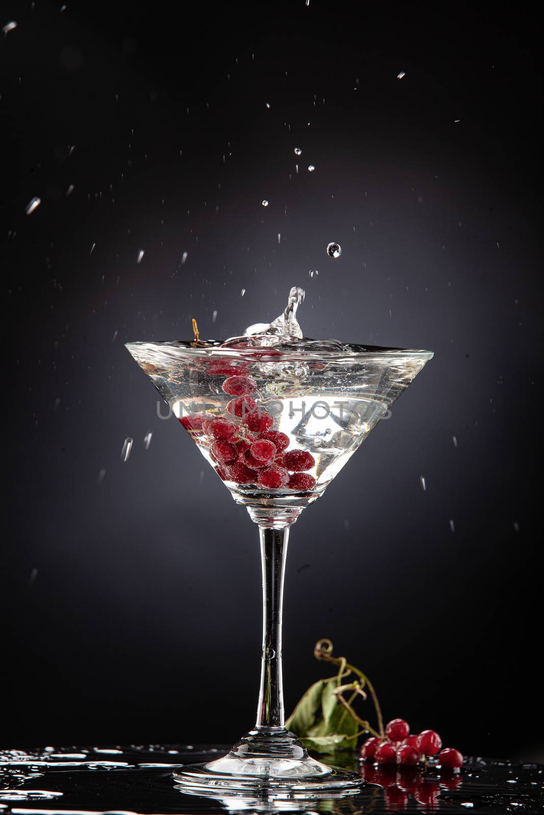 Bunch of red currant falling into the glass of water