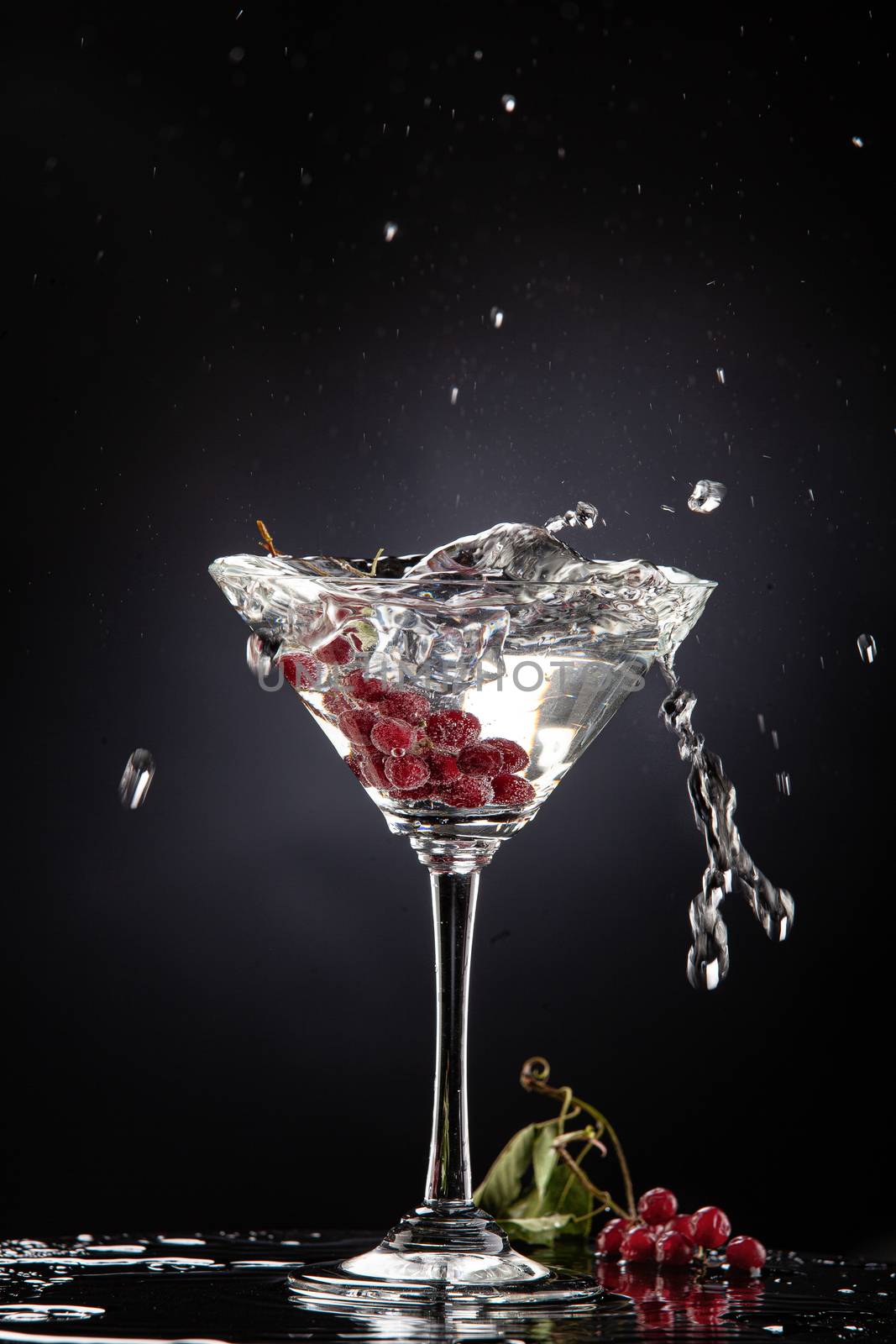 Bunch of red currant falling into the glass of water