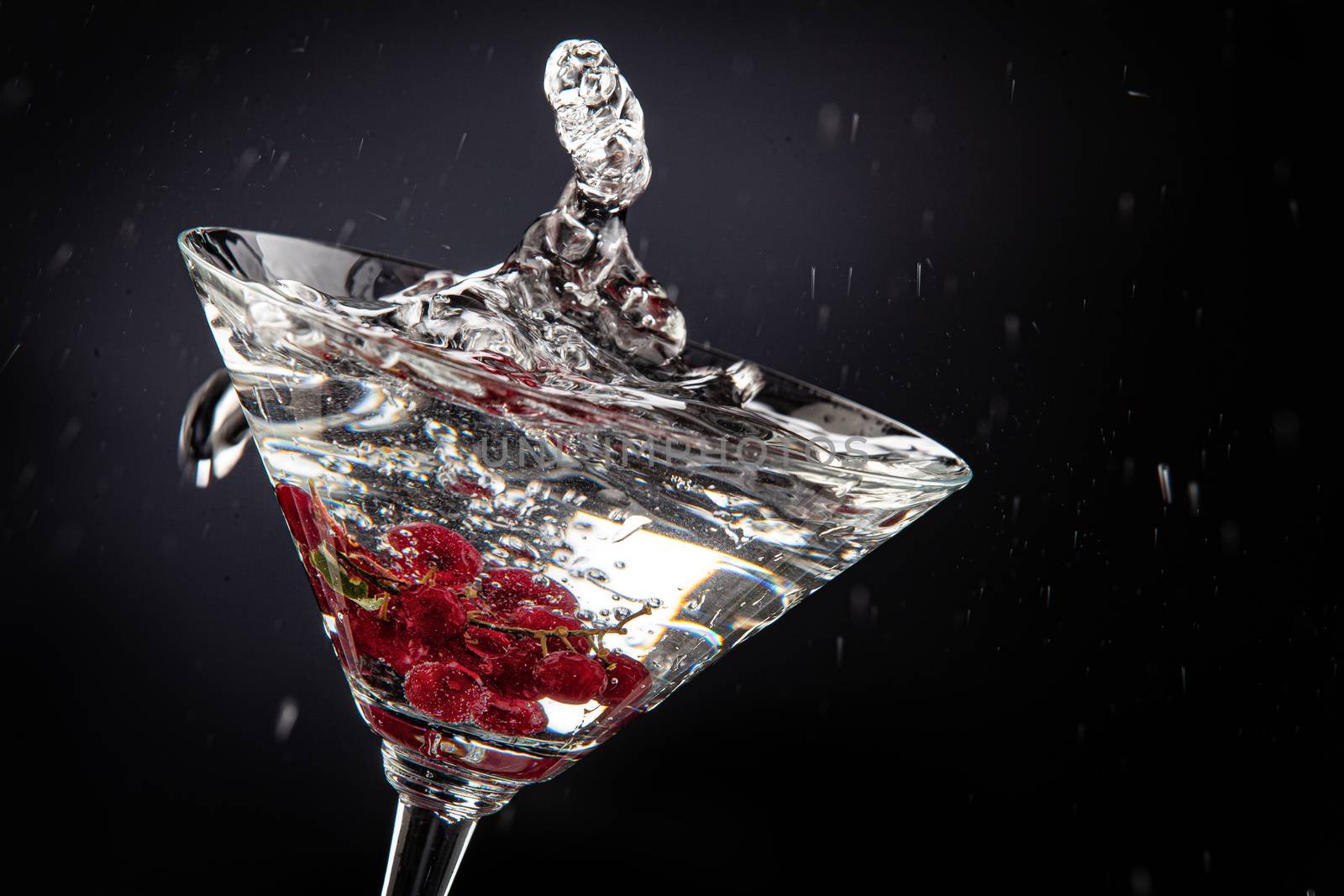 Bunch of red currant falling into the glass of water