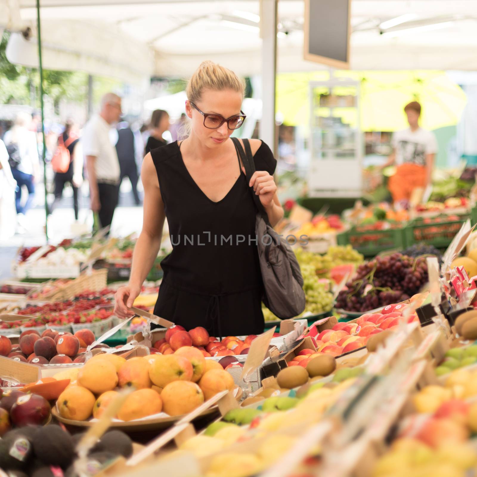 Woman buying fruits and vegetables at local food market. Market stall with variety of organic vegetable.