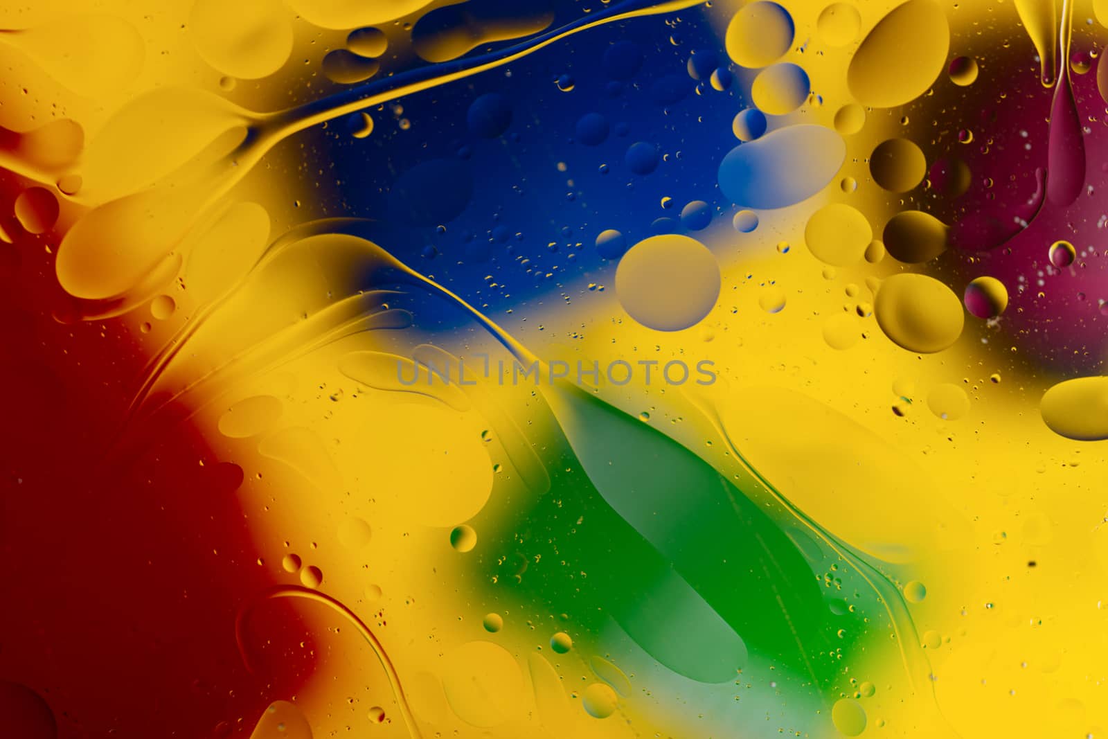 Abstract oil spots in motion on water on blurred yellow backgrou by alexsdriver