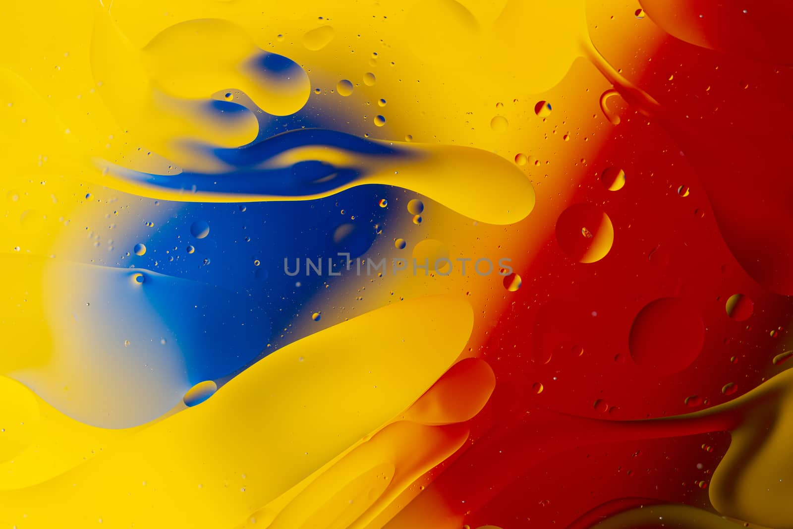 Abstract oil spots in motion on water on blurred yellow background. Red and blue spots on blurred background. Photo with small depth of field.