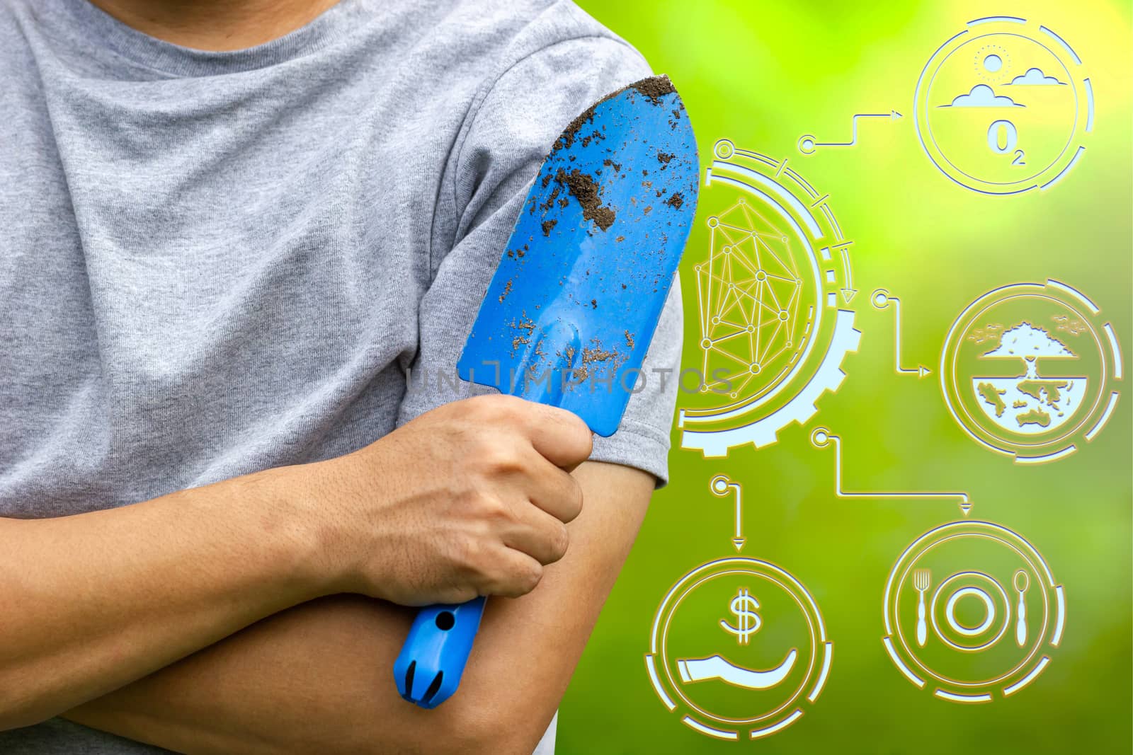 Gardener holding garden trowel and cross one's arm on green nature background. Concept of agriculture. Closeup and copy space for text.