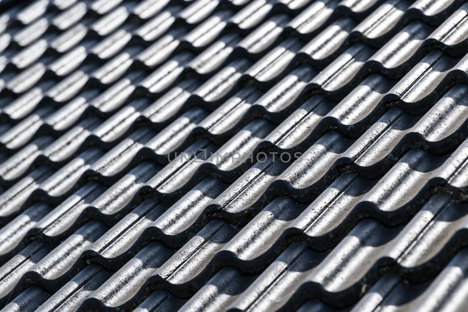 Abstract inclined roof surface with black concrete tiles in a high contrast as a background picture
