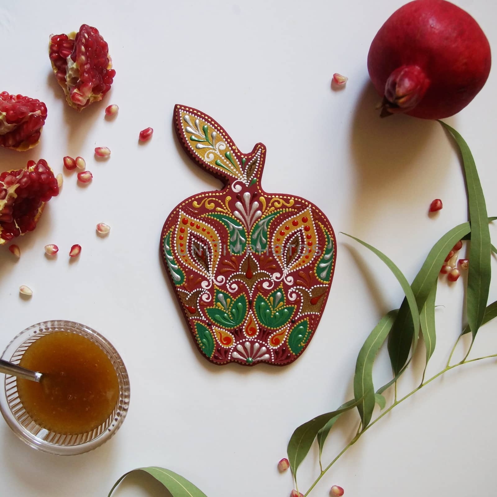 Rosh Hashanah Concept (Jewish New Year). Traditional symbols - pomegranate, honey and handmade apple, made from wood, painted with acrylic colors. Top view