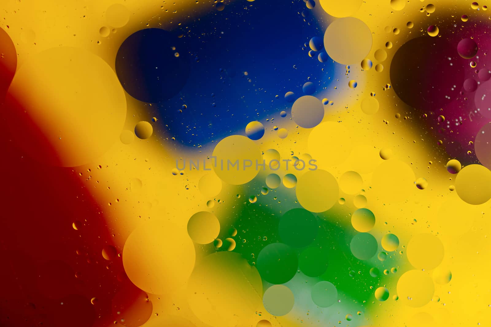 Abstract oil spots in motion on water on blurred yellow backgrou by alexsdriver