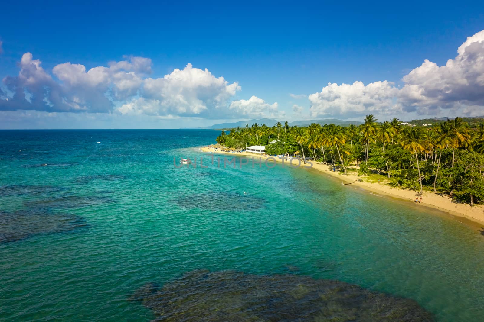 Aerial view of tropical beach with white boat anchored.Samana peninsula,Bahia Principe beach,Dominican Republic.