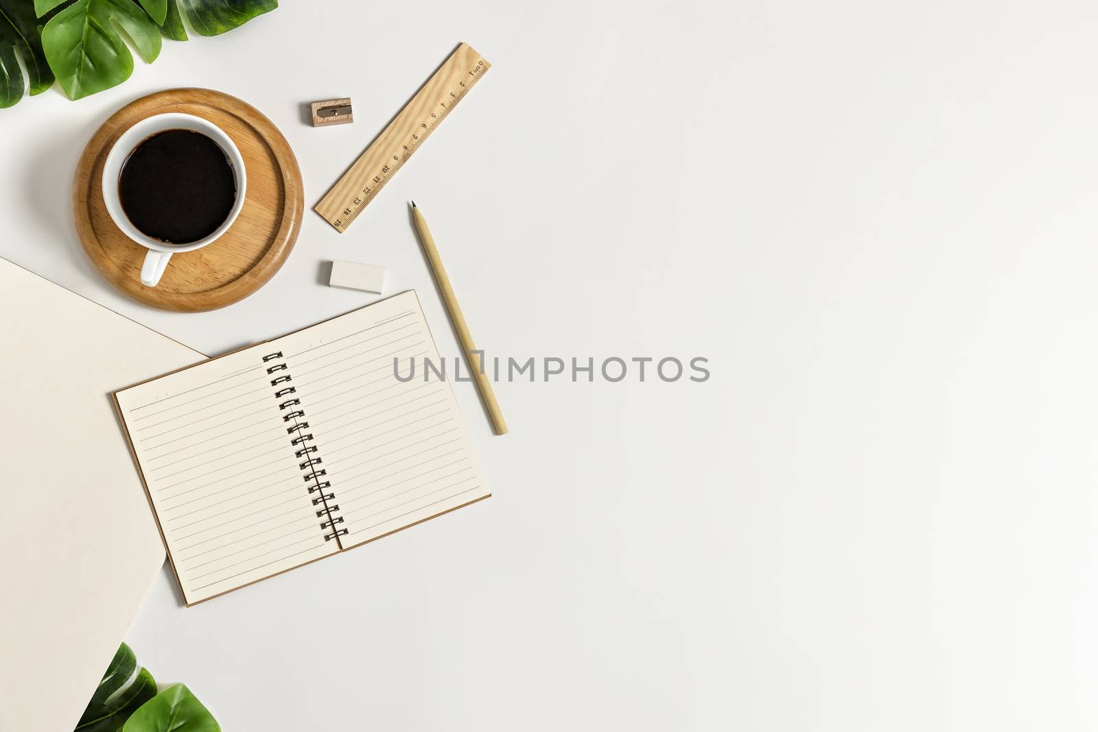 Flat lay of white office desk table with blank notebook, supplies and coffee cup. Top view with copy space.