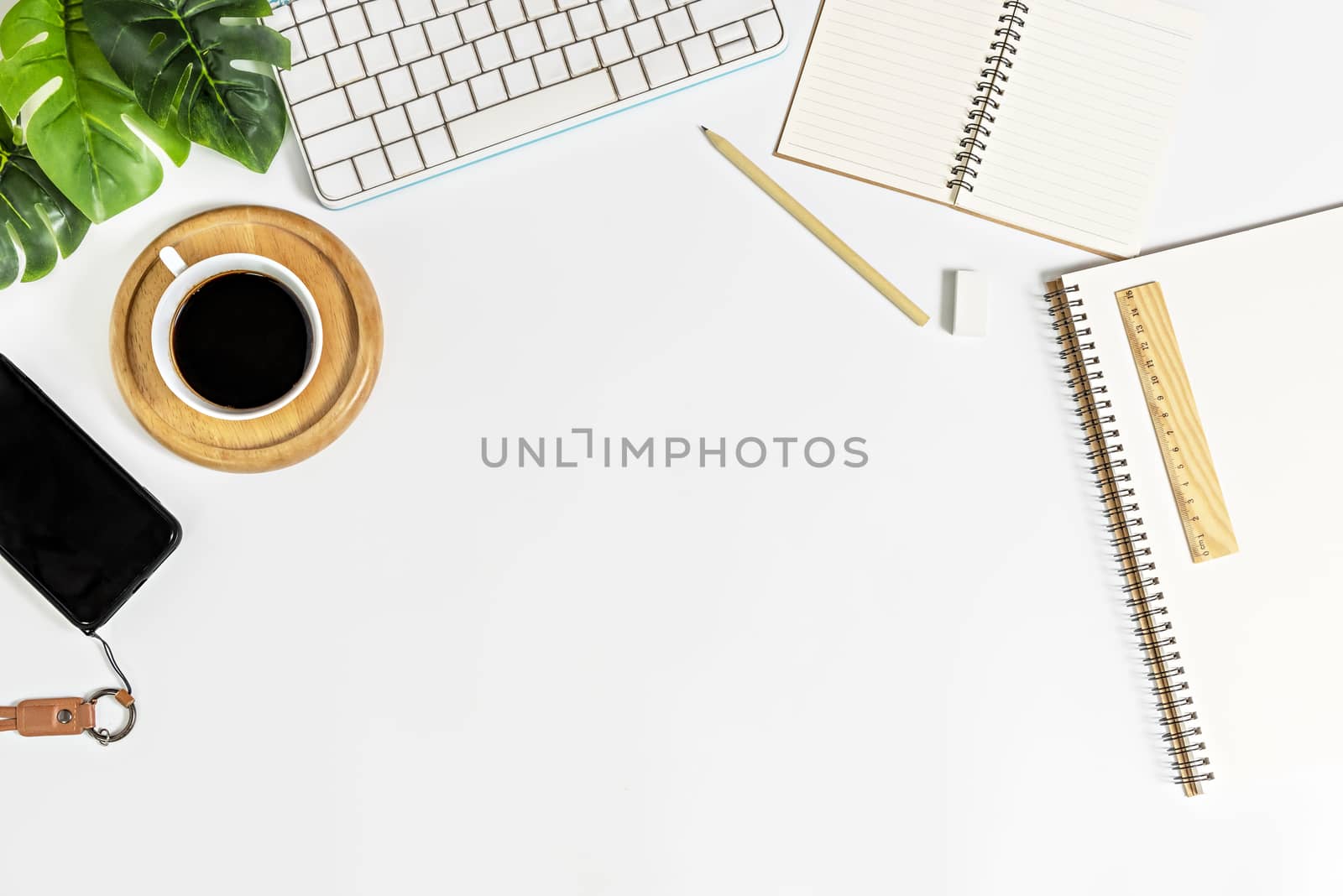 Flat lay of white office desk table with blank notebook, supplies and coffee cup. Top view with copy space.