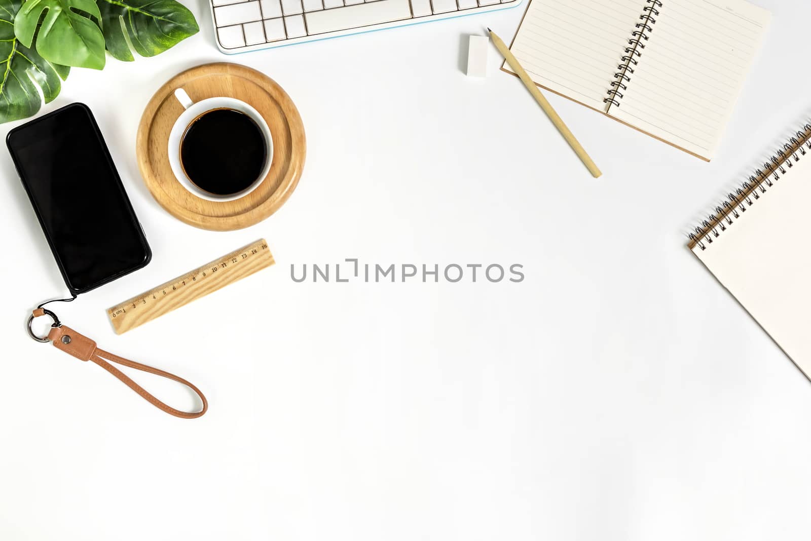 Flat lay of white office desk table with blank notebook, supplies and coffee cup. Top view with copy space.